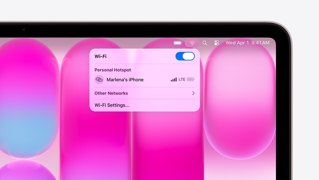 MacBook Neo maigi sārtā krāsā, Wi‑Fi izvēlnē tiek rādīta Personal Hotspot sadaļa ar izvēles iespēju ‟Marlena's iPhone”