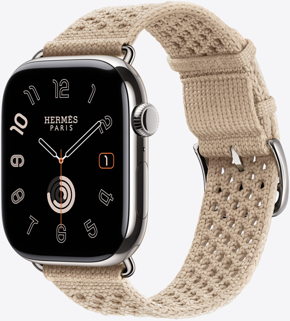 Apple Watch Hermès Series 11, titanium case, silver colour, polished finish, edge-to-edge display, rounded corners, right side exterior, Digital Crown, microphone, side button, Circular watch face (hour, minute, second hands, Hermès Paris logo), paired with Néo Tricot band, argile colour (beige), knit polyamide yarn material, adjustment holes centred, silver colour buckle and hardware