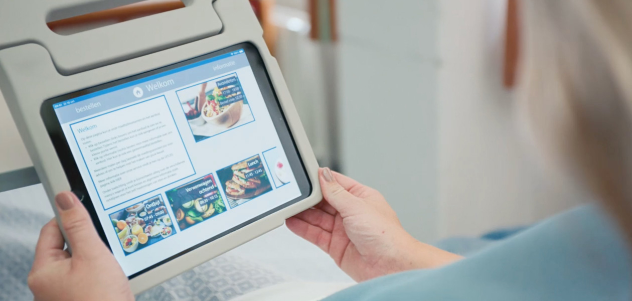 Une patiente consultant du contenu sur un Pad, assise sur son lit d’hôpital.
