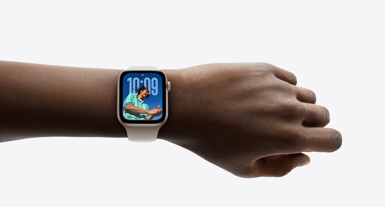 Cận cảnh Apple Watch màu Bạc với dây đeo chất liệu cao su trên cổ tay của một người, thể hiện ứng dụng Thời Gian với thiết kế Liquid Glass mới